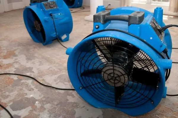 Blue air movers drying a subfloor after the flooring was pulled up in an Aliso Viejo home