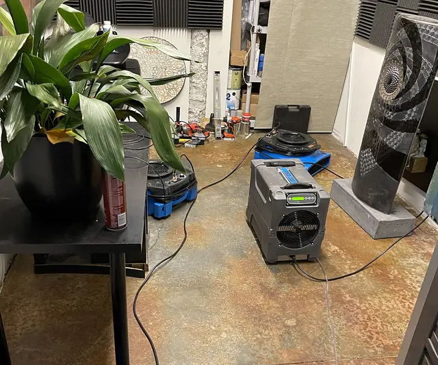 Dehumidifier and air mover drying a stained concrete floor in an Aliso Viejo room after the flooring came up