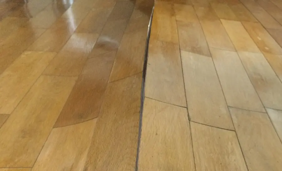 Wood floor boards lifting and buckling along a seam after a water leak